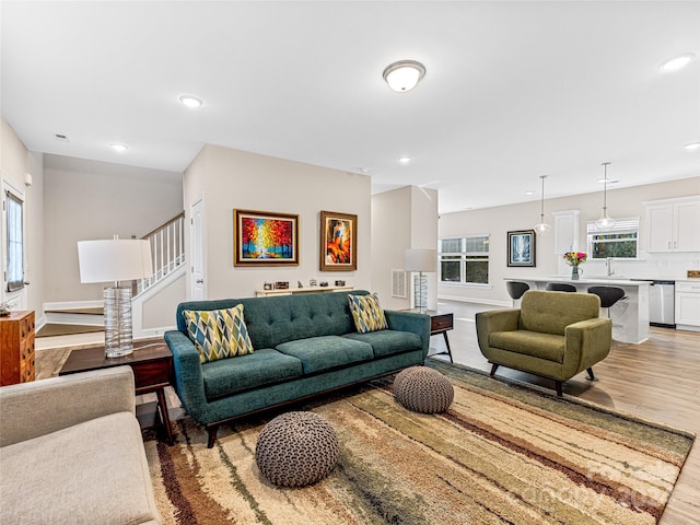 living room featuring light wood-type flooring, a wealth of natural light, and sink