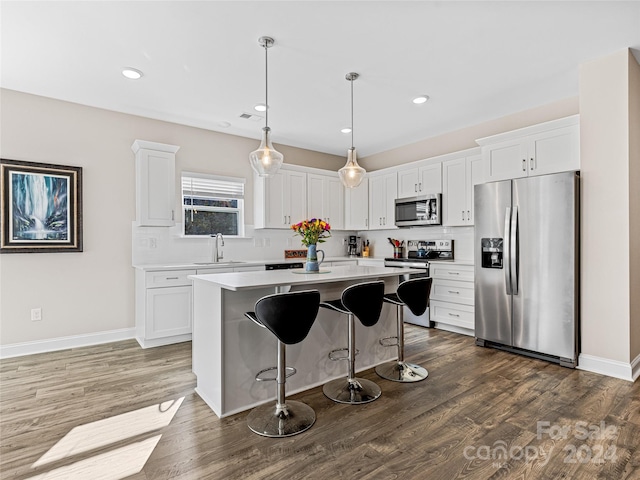 kitchen featuring dark hardwood / wood-style floors, white cabinetry, pendant lighting, and appliances with stainless steel finishes