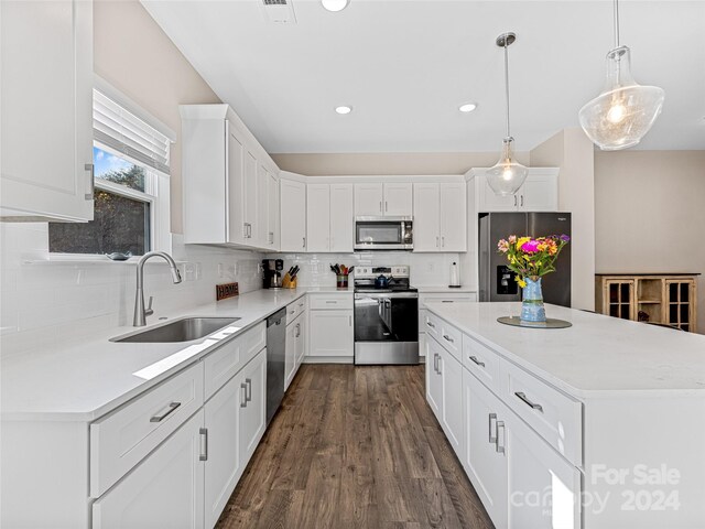 kitchen featuring appliances with stainless steel finishes, decorative light fixtures, sink, white cabinets, and a center island