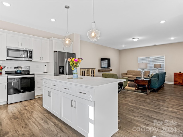 kitchen featuring wood-type flooring, pendant lighting, a kitchen island, white cabinetry, and appliances with stainless steel finishes