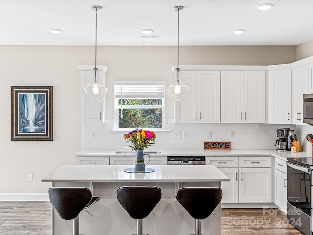 kitchen featuring light hardwood / wood-style flooring, white cabinetry, pendant lighting, and stainless steel appliances