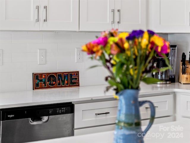 interior details with dishwasher, backsplash, and white cabinets