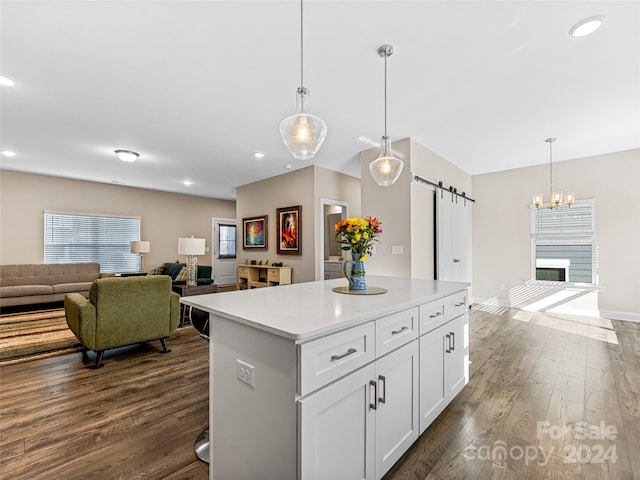 kitchen featuring white cabinets, a barn door, decorative light fixtures, and dark hardwood / wood-style floors