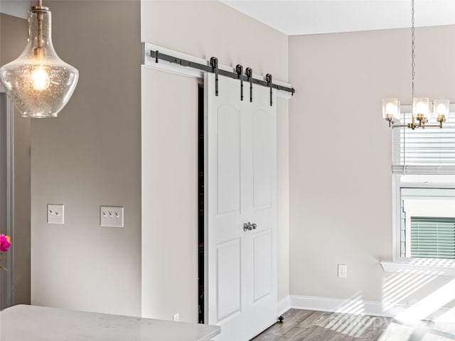 bedroom with hardwood / wood-style floors, a barn door, and a notable chandelier