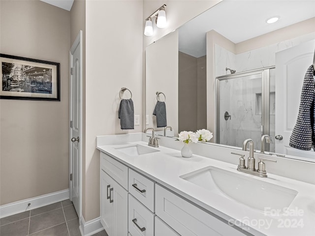 bathroom with a shower with shower door, vanity, and tile patterned floors