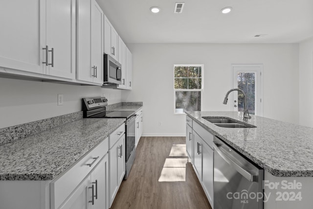 kitchen featuring appliances with stainless steel finishes, white cabinets, sink, and a center island with sink