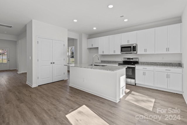 kitchen featuring white cabinets, an island with sink, sink, light hardwood / wood-style floors, and stainless steel appliances