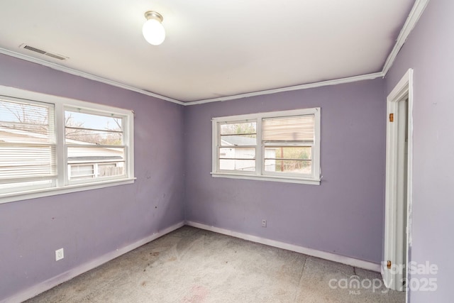 spare room featuring visible vents, plenty of natural light, baseboards, and crown molding