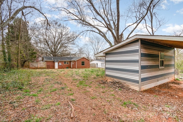 view of yard featuring an outdoor structure, fence, driveway, and a carport