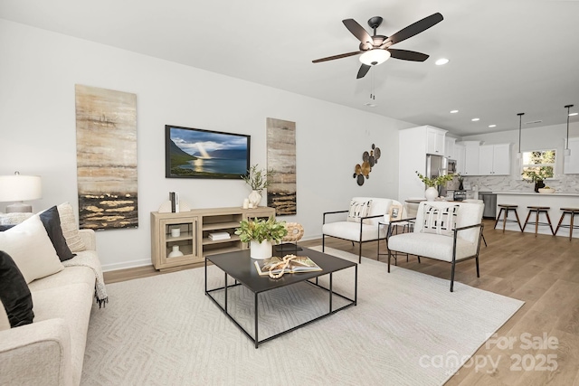 living room with light wood-type flooring and ceiling fan