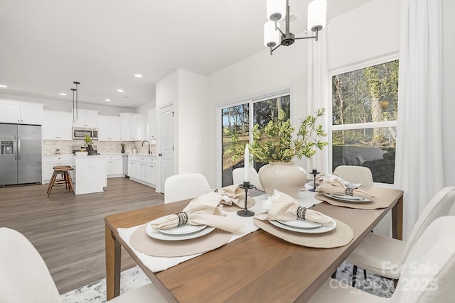 dining room with a notable chandelier, plenty of natural light, light wood-type flooring, and sink