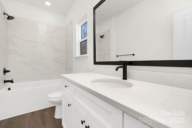 full bathroom featuring vanity, wood-type flooring, tiled shower / bath combo, and toilet