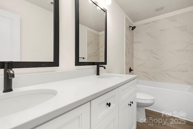 full bathroom featuring vanity, toilet, wood-type flooring, and tiled shower / bath