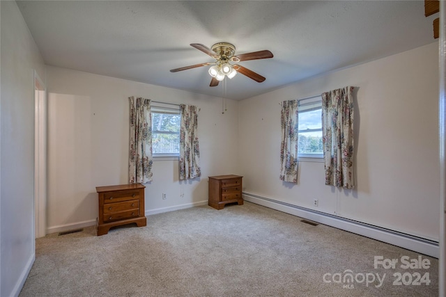 empty room featuring light carpet, baseboard heating, ceiling fan, and plenty of natural light