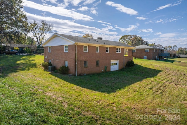 back of house featuring a garage, a yard, and cooling unit