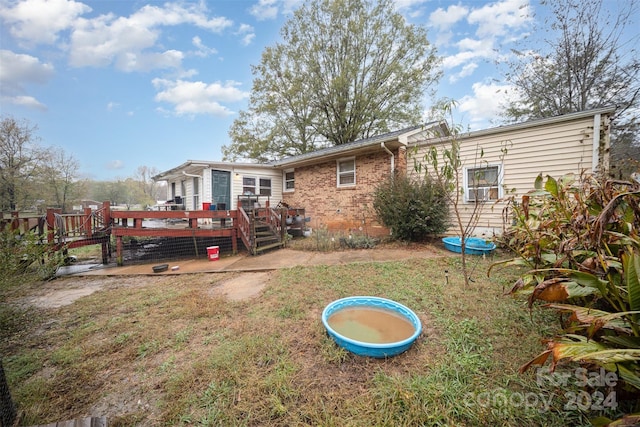 back of house featuring a lawn and a deck