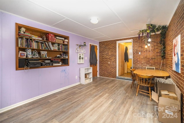 dining space featuring hardwood / wood-style flooring and brick wall