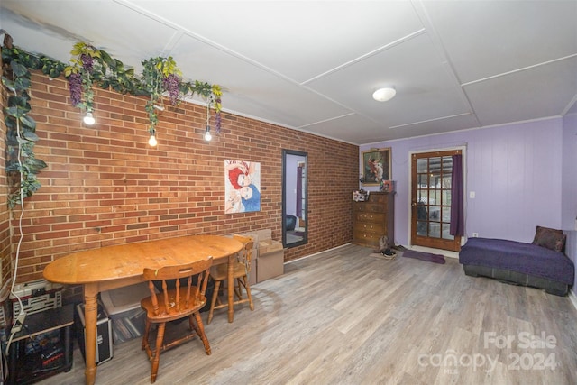 dining area featuring light wood-type flooring and brick wall