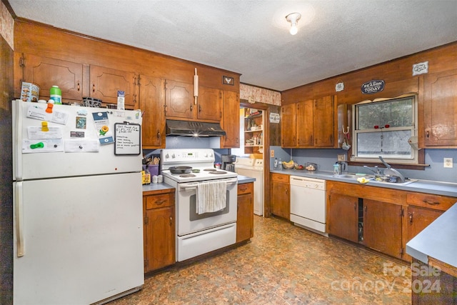 kitchen featuring wood walls, white appliances, sink, a textured ceiling, and washer / dryer