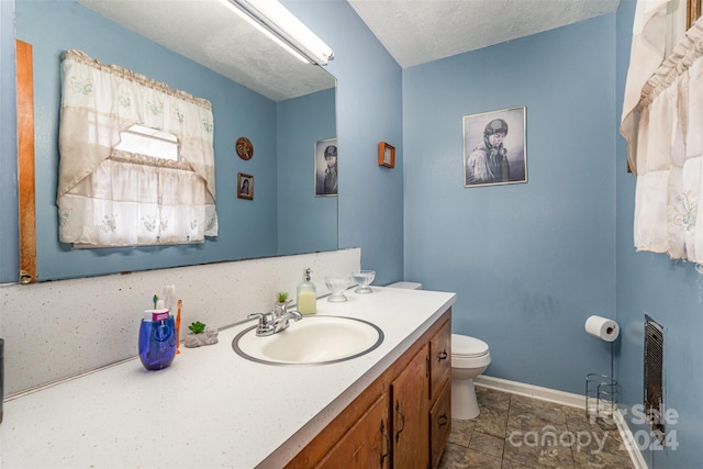 bathroom featuring a textured ceiling, vanity, and toilet