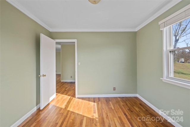 spare room with light hardwood / wood-style floors, crown molding, and a healthy amount of sunlight