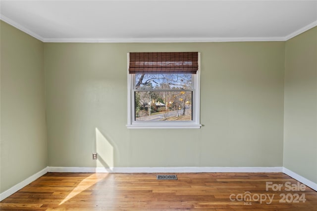 empty room with wood-type flooring and crown molding