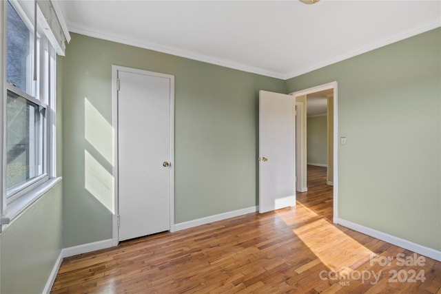 unfurnished bedroom featuring hardwood / wood-style flooring and crown molding