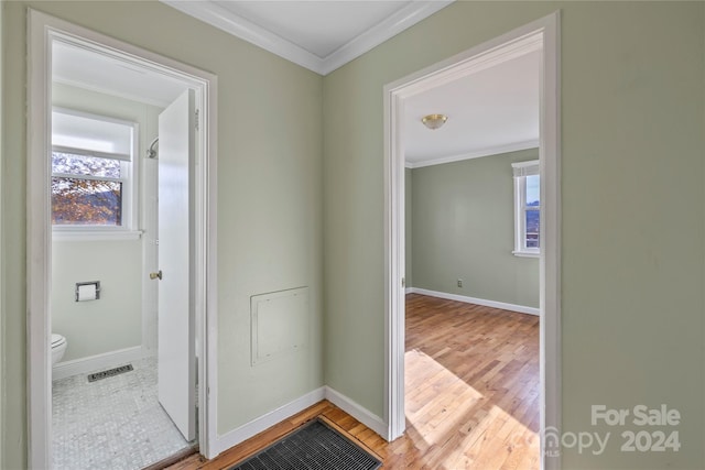 hall with light wood-type flooring and ornamental molding