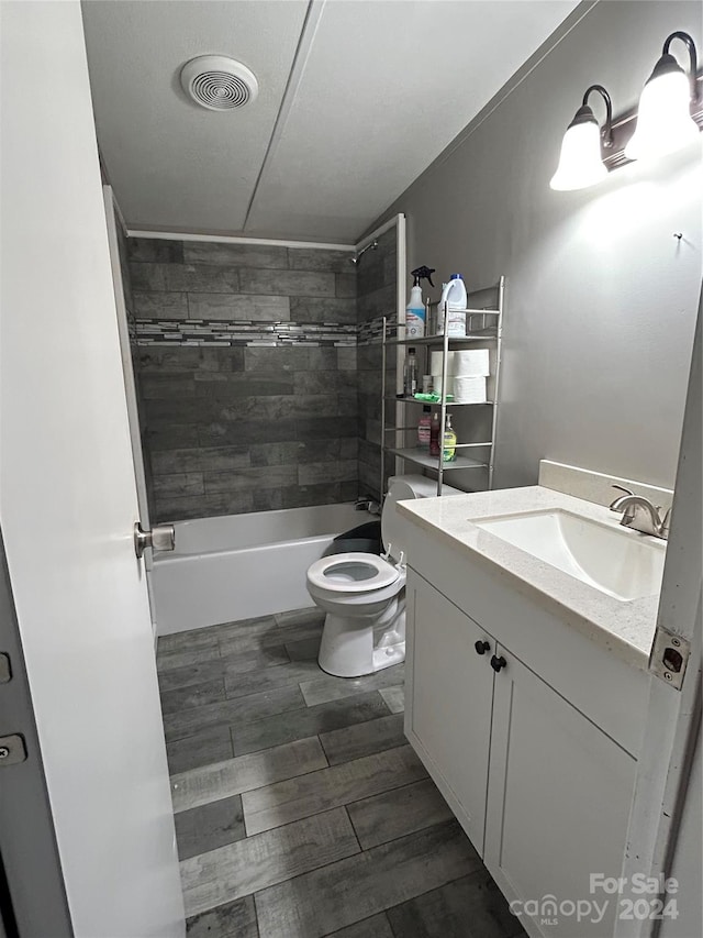 full bathroom featuring toilet, tiled shower / bath combo, vanity, and wood-type flooring