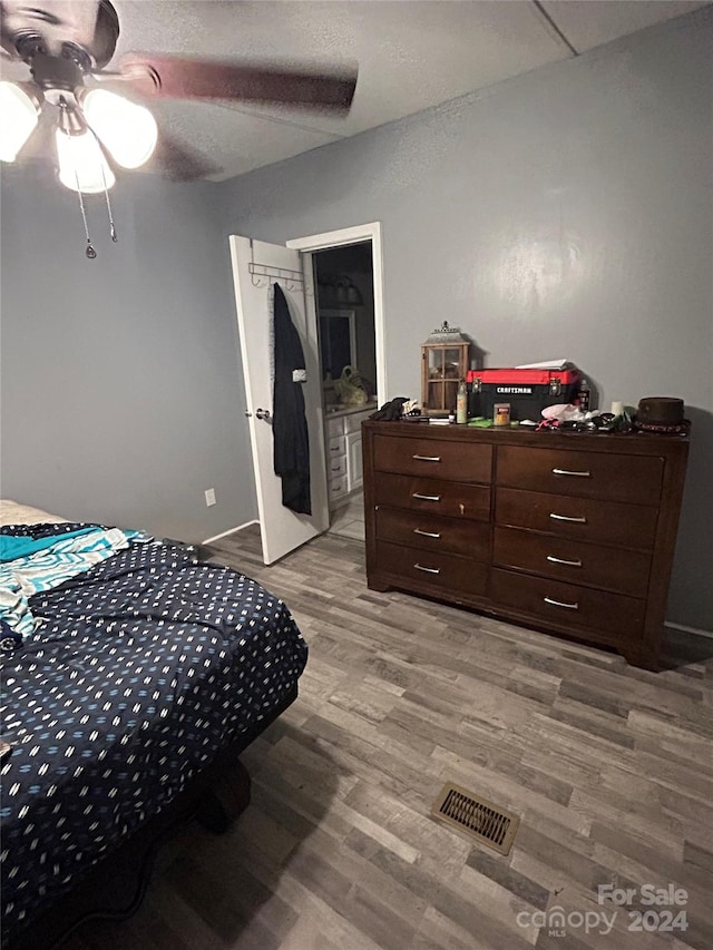 bedroom with ceiling fan, connected bathroom, light wood-type flooring, and a textured ceiling