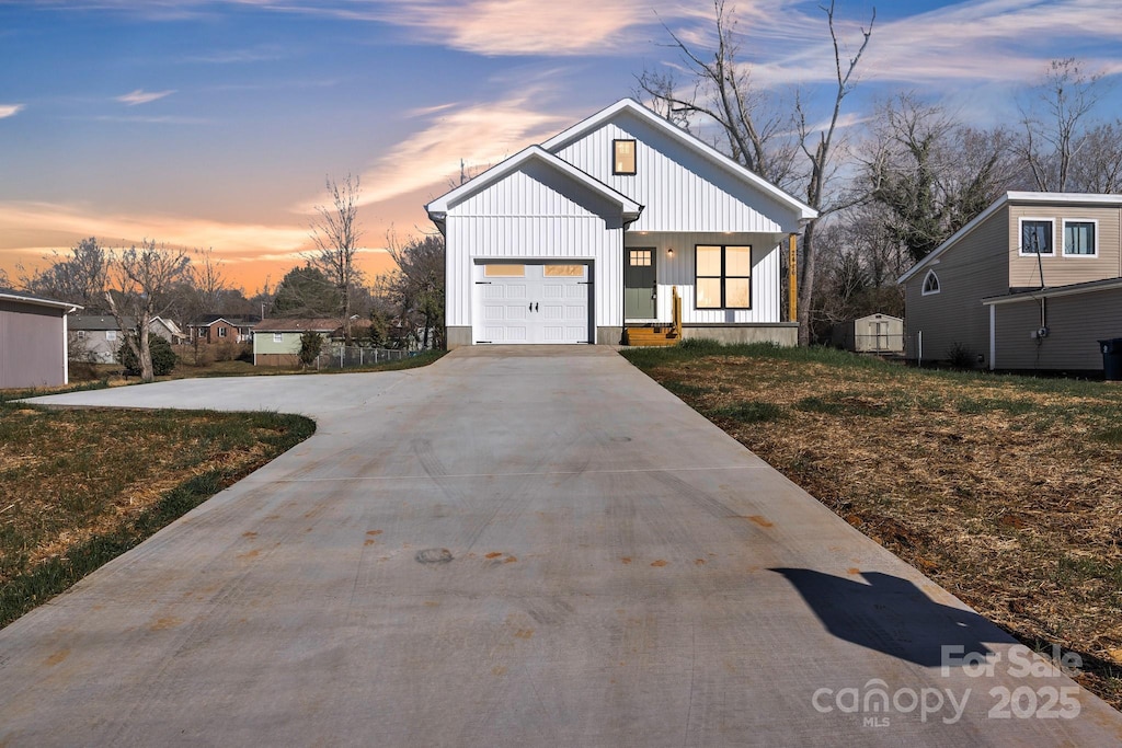 modern farmhouse style home featuring a garage, covered porch, and a lawn