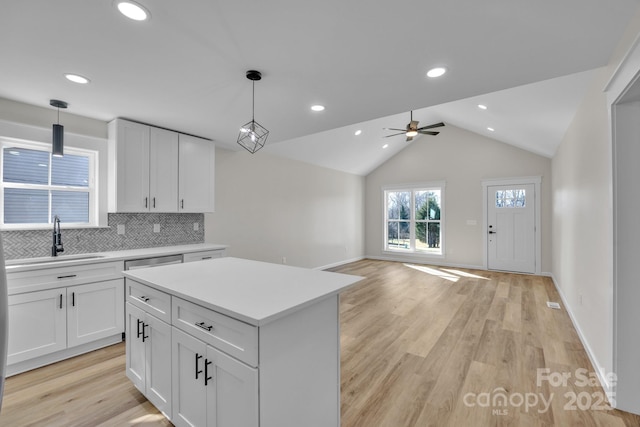 kitchen featuring pendant lighting, sink, a kitchen island, and white cabinets