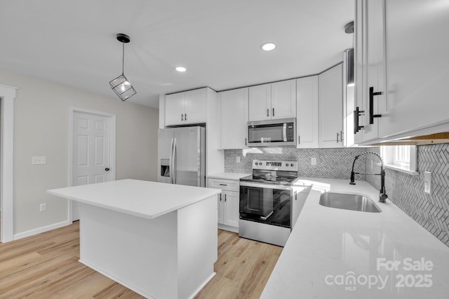 kitchen featuring stainless steel appliances, sink, pendant lighting, and white cabinets