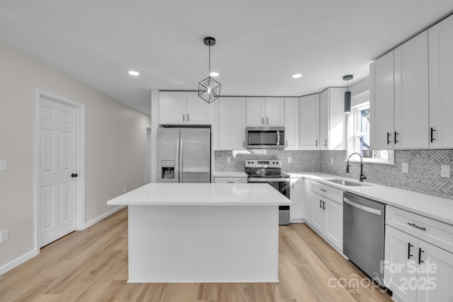 kitchen featuring pendant lighting, sink, appliances with stainless steel finishes, white cabinetry, and a kitchen island