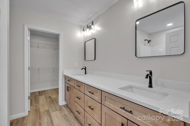 bathroom with hardwood / wood-style flooring, vanity, and walk in shower