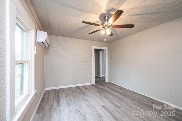 unfurnished room with a wealth of natural light, ceiling fan, a wall mounted AC, and wood-type flooring