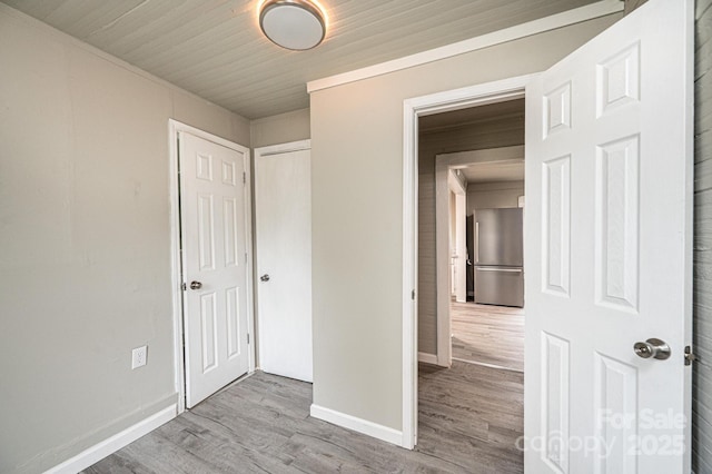 unfurnished bedroom featuring light wood-type flooring and stainless steel refrigerator