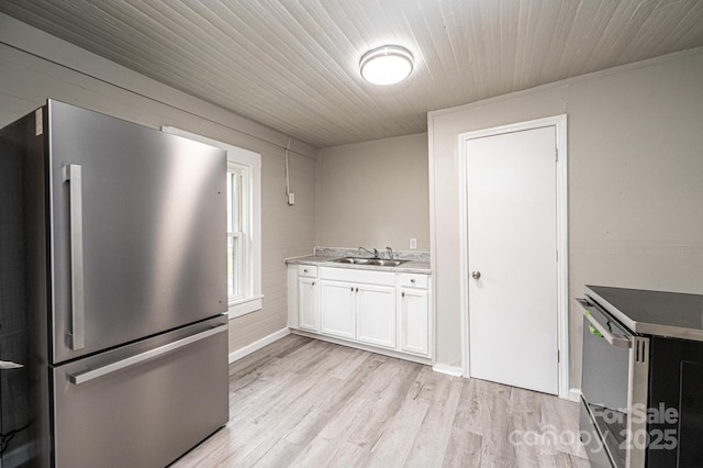 kitchen with stainless steel fridge, sink, white cabinets, and light wood-type flooring