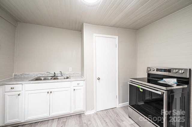 kitchen with stainless steel range with electric stovetop, white cabinets, sink, and light hardwood / wood-style flooring