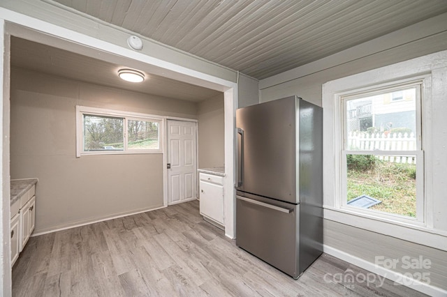 kitchen with white cabinetry, stainless steel fridge, light hardwood / wood-style floors, and wooden ceiling