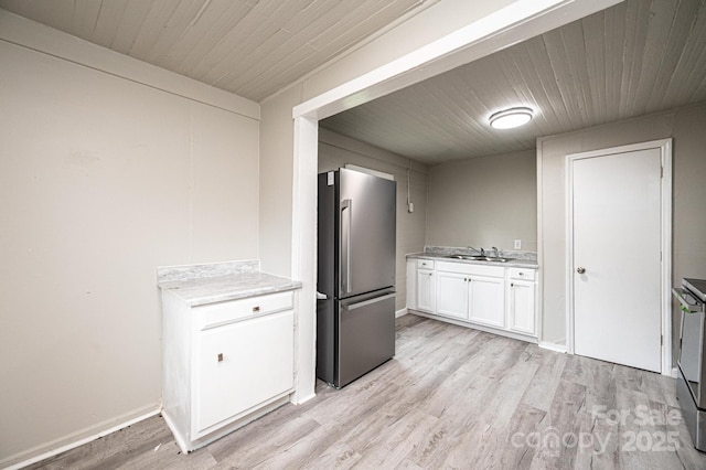 kitchen featuring stainless steel fridge, light wood-type flooring, sink, white cabinets, and range