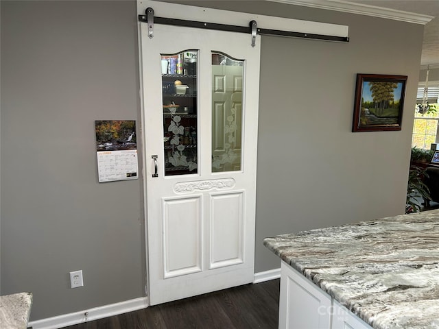 interior space with hardwood / wood-style floors, a barn door, and ornamental molding