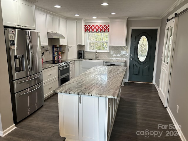 kitchen featuring a barn door, white cabinets, a kitchen island, and appliances with stainless steel finishes