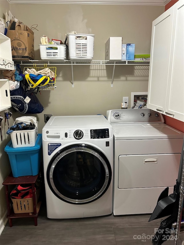 clothes washing area featuring separate washer and dryer, dark wood-type flooring, and cabinets