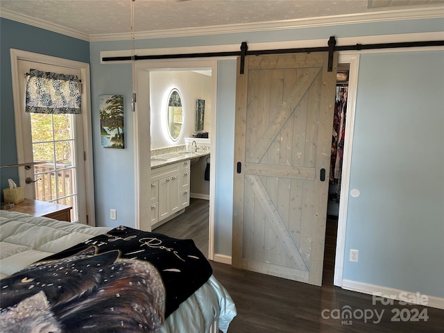 bedroom featuring crown molding, dark hardwood / wood-style floors, a barn door, a textured ceiling, and connected bathroom