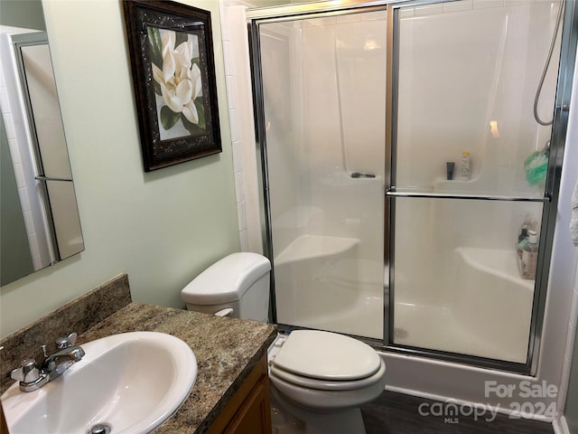 bathroom with hardwood / wood-style floors, vanity, a shower with shower door, and toilet