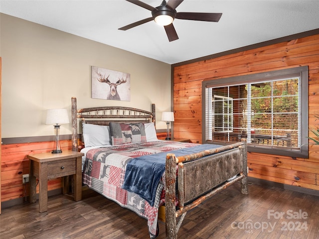 bedroom featuring hardwood / wood-style floors, ceiling fan, and wooden walls