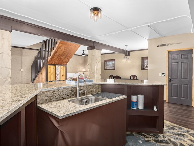 kitchen with kitchen peninsula, dark hardwood / wood-style flooring, sink, and light stone countertops