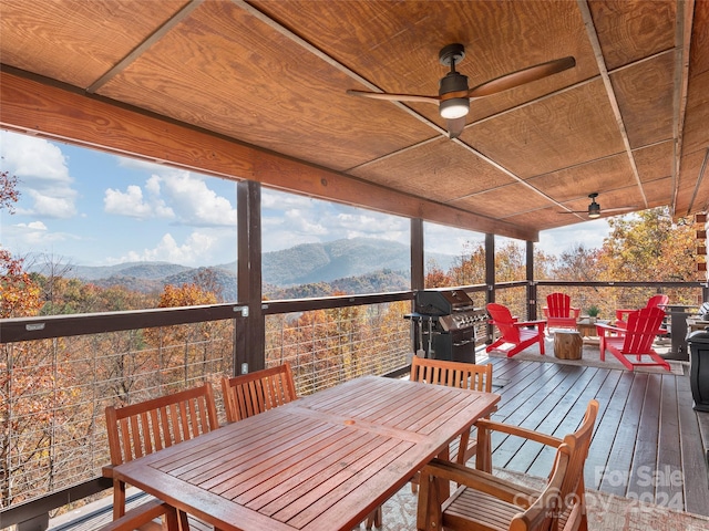 sunroom featuring ceiling fan, a mountain view, and wood ceiling