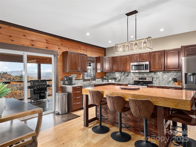 kitchen featuring tasteful backsplash, appliances with stainless steel finishes, butcher block counters, and light hardwood / wood-style flooring